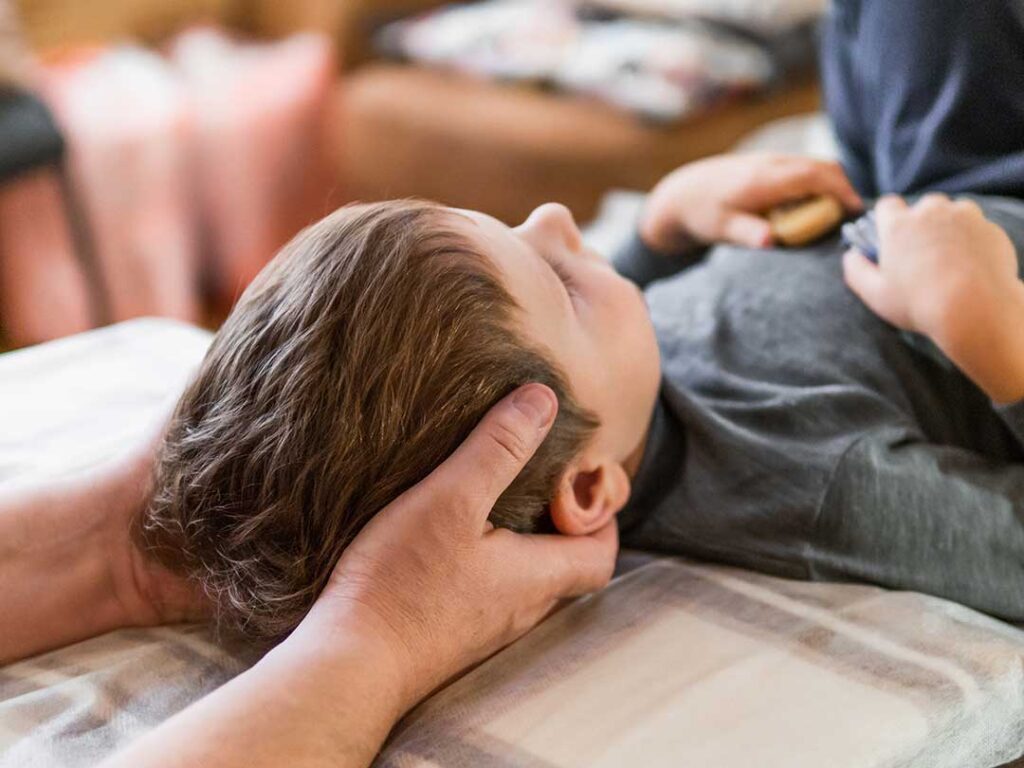 Woman using a heating pad while tracking menstrual symptoms in a notebook at home.